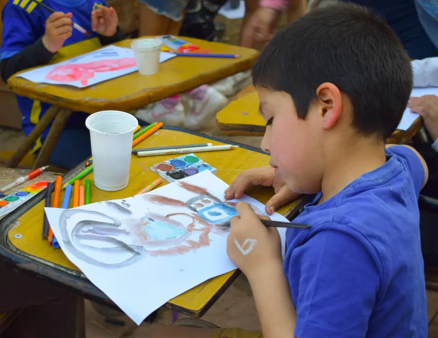 Una nena pinta con acuarelas sobre una hoja en la mesa del taller de arte.