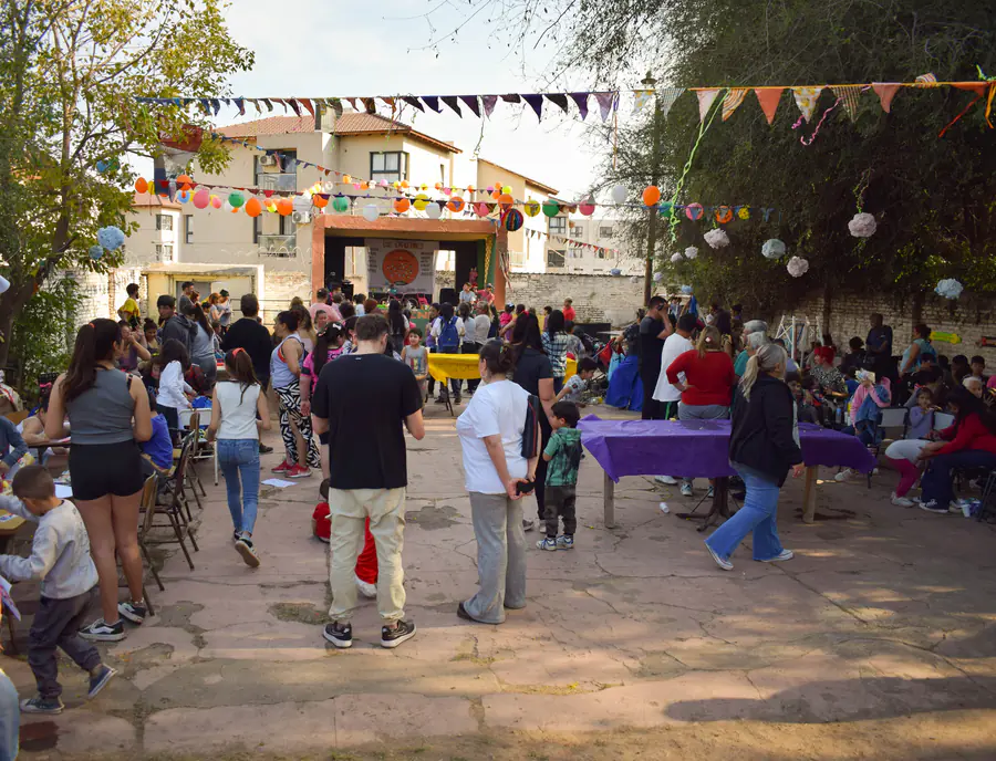 Vista amplia del patio con familias, mesas y guirnaldas durante una jornada comunitaria.