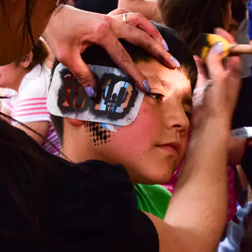 Primer plano de un nene mientras le terminan de pintar la cara.