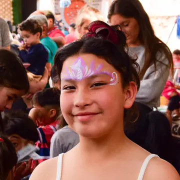 Chica sonriente con mariposa pintada en la frente.