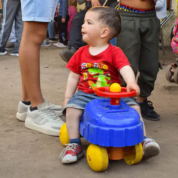 Nene muy chico sentado en un autito de juguete recién recibido.