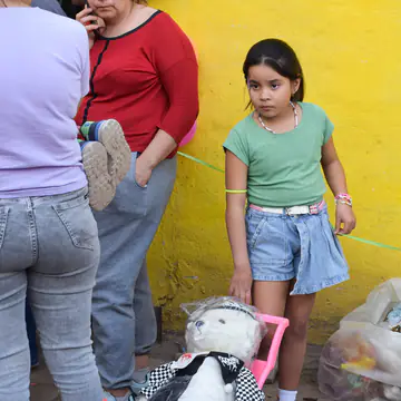 Dos nenas junto a la pared amarilla con un cochecito de juguete.