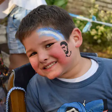 Nene con la cara pintada de celeste y blanco.