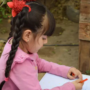 Nena de trenza pintando con témpera en el taller.
