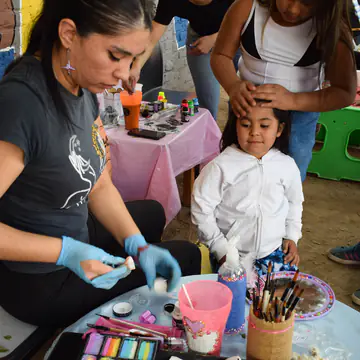 Voluntaria prepara los potes de pintura sobre la mesa del taller.