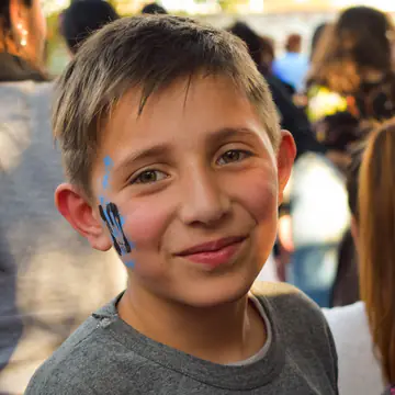 Nene sonríe con una banderita pintada en el cachete.