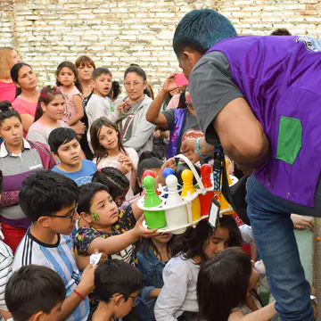 Un voluntario entrega un juguete entre muchas manos levantadas.