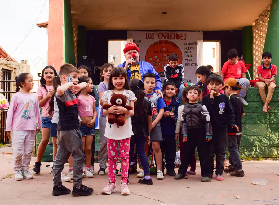 Un grupo grande de chicos y chicas posa en la puerta verde y naranja del espacio.