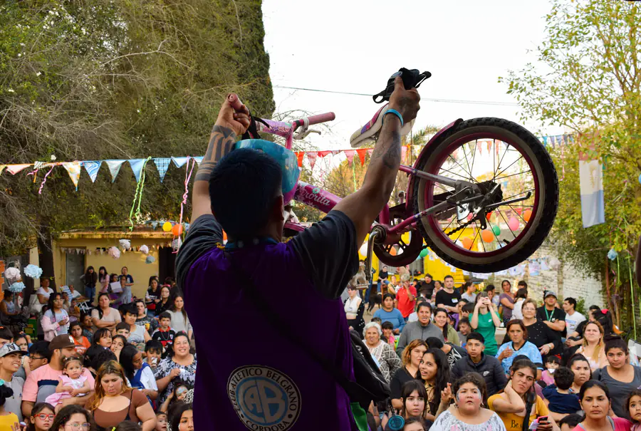 Un voluntario levanta una bicicleta para entregarla frente a una multitud de chicos.
